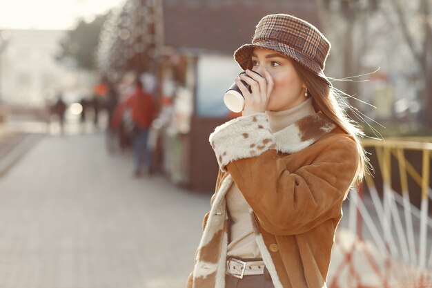 Chica caminando en una ciudad de primavera y tomando café