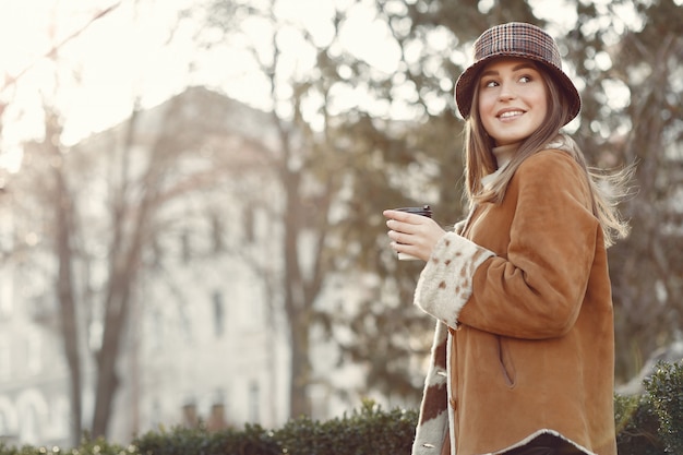 Chica caminando en una ciudad de primavera y tomando café
