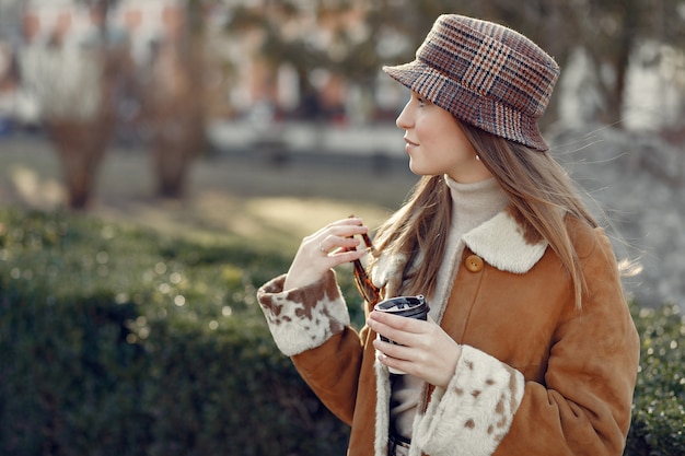 Chica caminando en una ciudad de primavera y tomando café