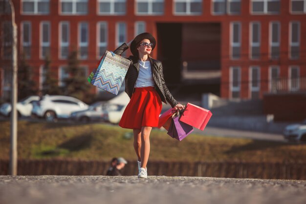 Chica caminando con compras en calles de la ciudad