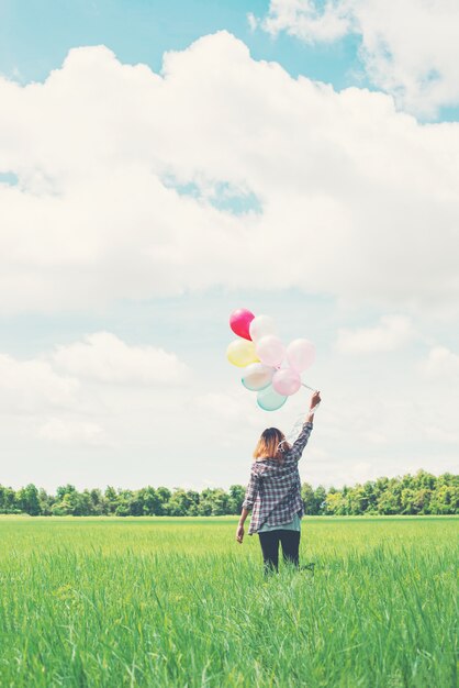 Chica caminando con globos en el prado