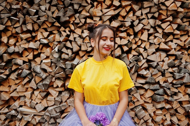Foto gratuita chica en camisa amarilla con flores de aster violeta en las manos