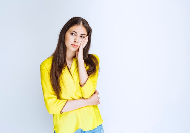 La chica con camisa amarilla parece confundida y dudosa.