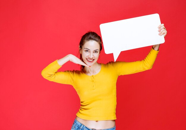 Chica en camisa amarilla sosteniendo un tablero de información rectangular