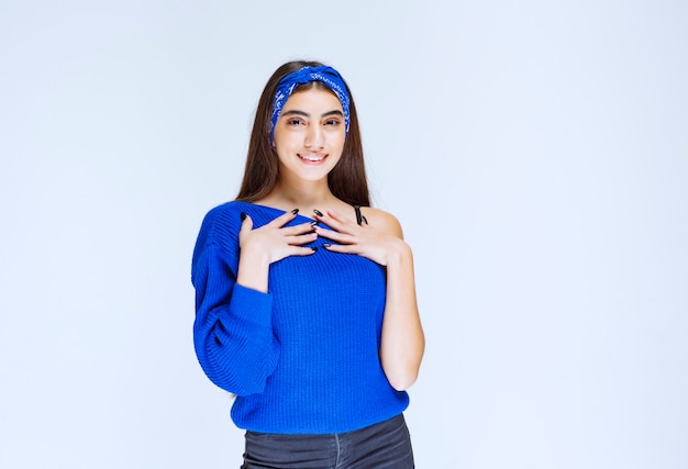 Chica con camisa azul apuntando a sí misma.