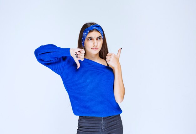 Chica con camisa azul mostrando el pulgar hacia arriba y hacia abajo.