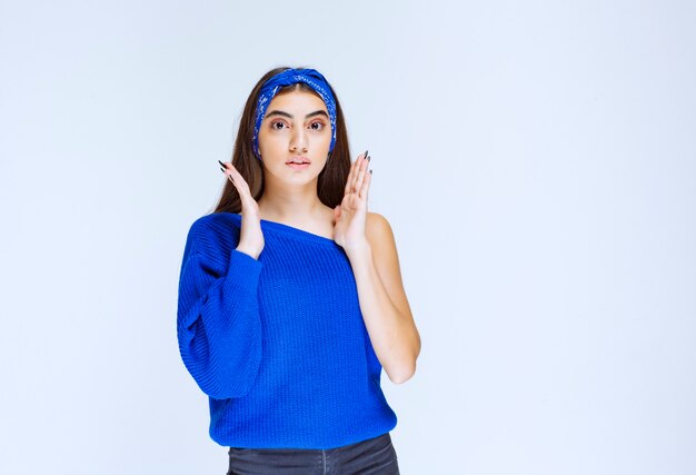 Chica con camisa azul parece asustada y aterrorizada.