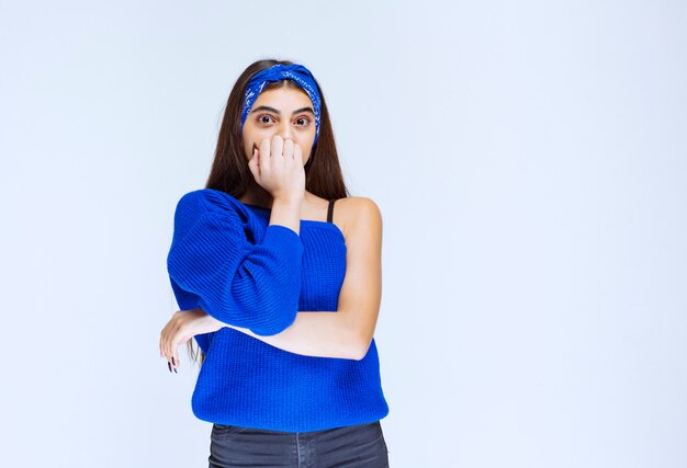 Chica con camisa azul parece asustada y aterrorizada.