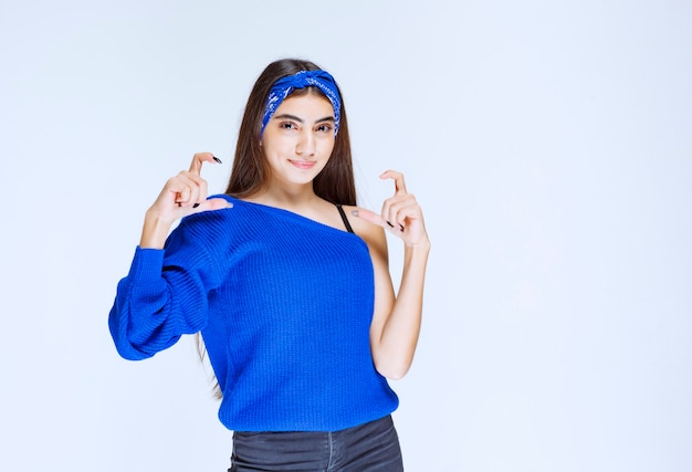 Chica con camisa azul que muestra el tamaño de un objeto.