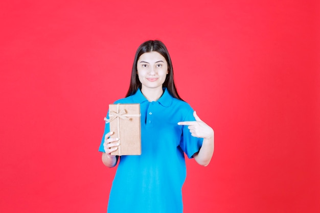 Chica en camisa azul sosteniendo una mini caja de regalo de cartón