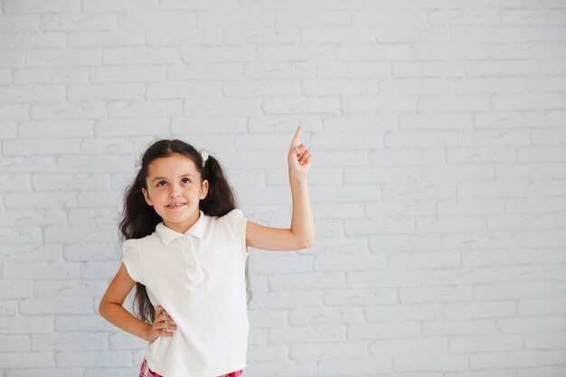 Chica en camisa blanca apuntando hacia arriba