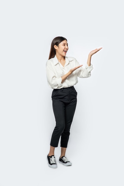 La chica con una camisa blanca y el signo de la mano abierta en el lateral.