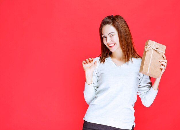 Chica con camisa blanca sosteniendo una caja de regalo y parece sorprendida.