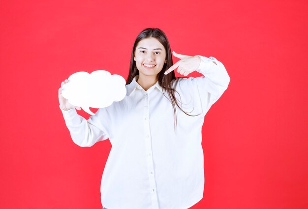 Chica en camisa blanca sosteniendo un tablero de información de forma de nube