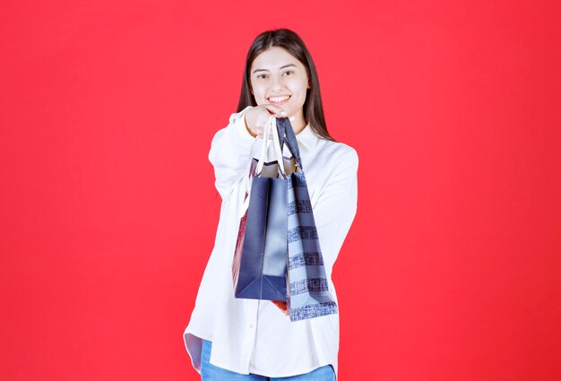 Chica con camisa blanca sosteniendo varias bolsas de la compra.