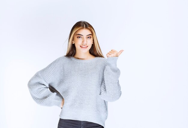 Chica de la camisa gris apuntando a algún lugar o alguien.