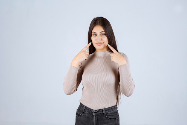 Foto gratuita chica con camisa gris apuntando a su boca.