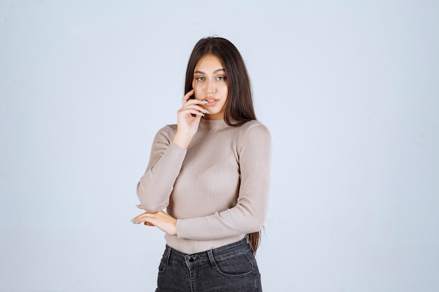 Chica en camisa gris dando poses positivas y atractivas.