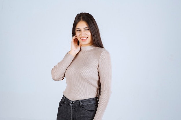 Chica en camisa gris dando poses positivas y atractivas.