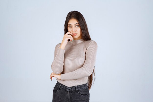 Chica en camisa gris dando poses positivas y atractivas.