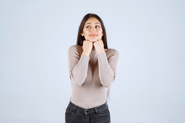 Chica en camisa gris dando poses positivas y atractivas.