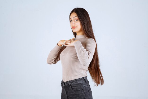 Chica en camisa gris dando poses positivas y atractivas.