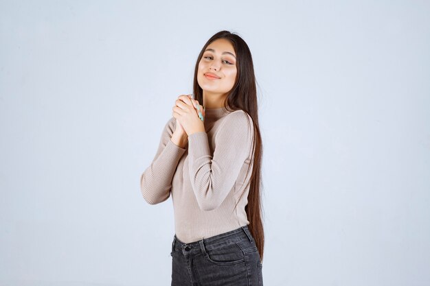 Chica en camisa gris dando poses positivas y atractivas.