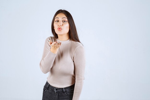 Chica con camisa gris enviando amor a sus fans.