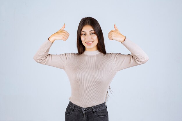 Chica en camisa gris haciendo pulgar arriba signo.