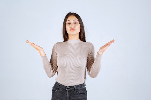 Chica con camisa gris mostrando las medidas estimadas de un objeto.