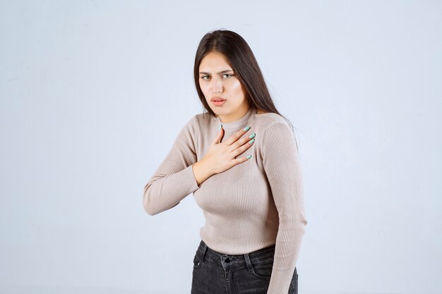 Chica con camisa gris parece asustada y asustada.