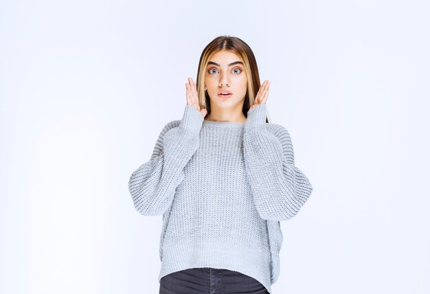 Chica con camisa gris parece asustada y aterrorizada.