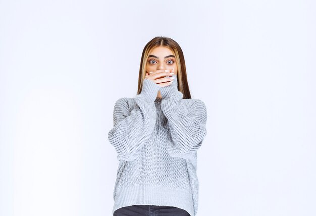 Chica con camisa gris parece asustada y aterrorizada.