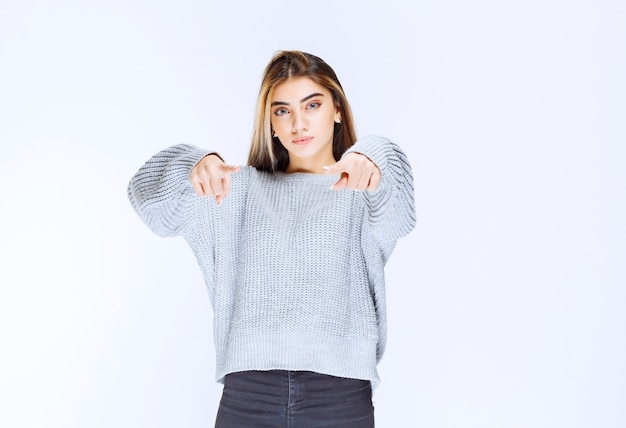 Foto gratuita chica con camisa gris que muestra a alguien por delante.