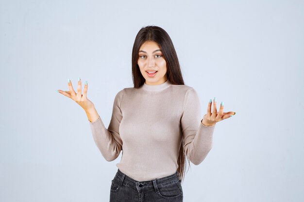 La chica con camisa gris se ve emocionada y sorprendida.