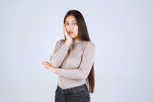 La chica con camisa gris se ve emocionada y sorprendida.