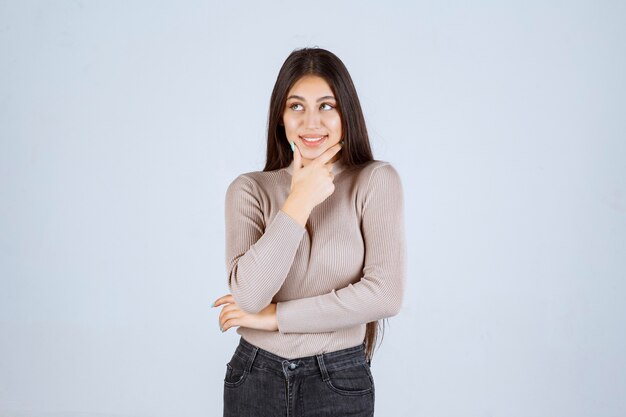 La chica con camisa gris se ve emocionada y sorprendida.