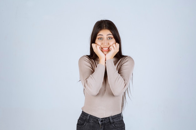 La chica con camisa gris se ve emocionada.