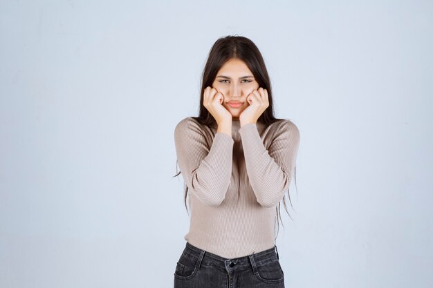 La chica con camisa gris se ve emocionada.