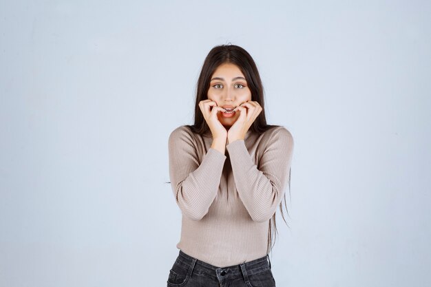 La chica con camisa gris se ve emocionada.