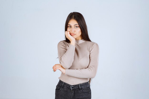 La chica con camisa gris se ve pensativa y confundida.