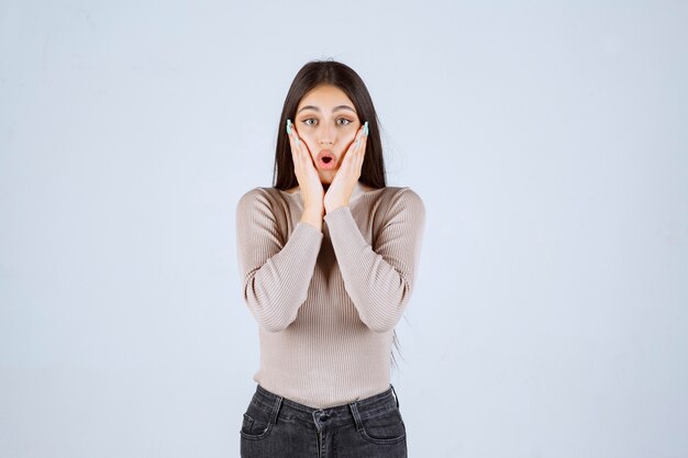 La chica con camisa gris se ve sorprendida y confundida.