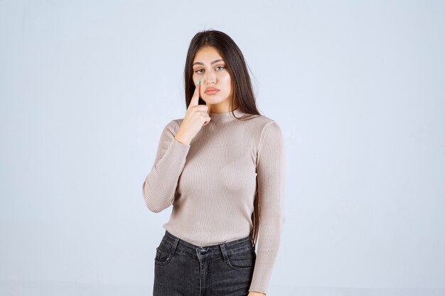 La chica con camisa gris se ve sorprendida y confundida.