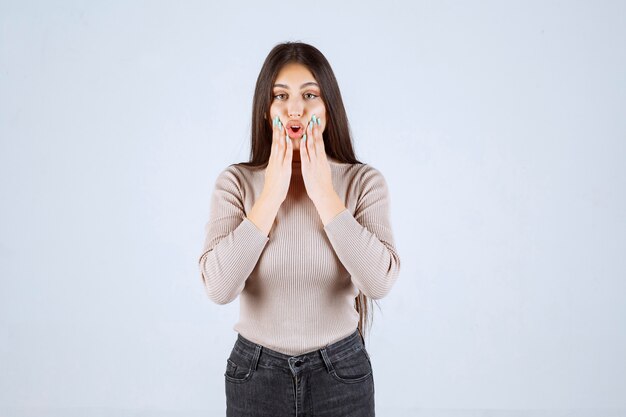 La chica con camisa gris se ve sorprendida y confundida.