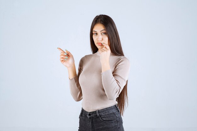 La chica con camisa gris se ve sorprendida y confundida.