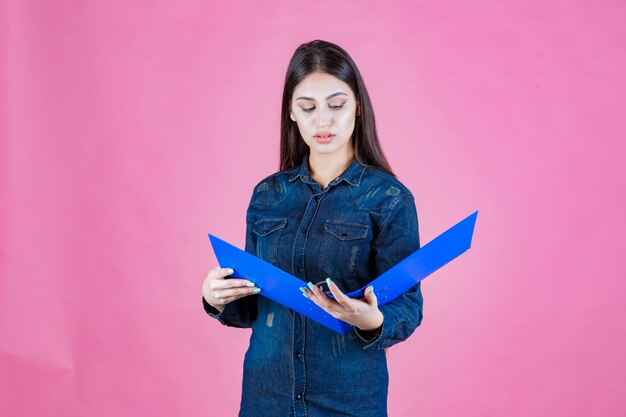 Chica en camisa de mezclilla leyendo informes