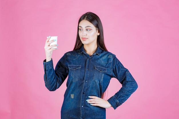 Chica en camisa de mezclilla sosteniendo una taza de café y se siente positiva