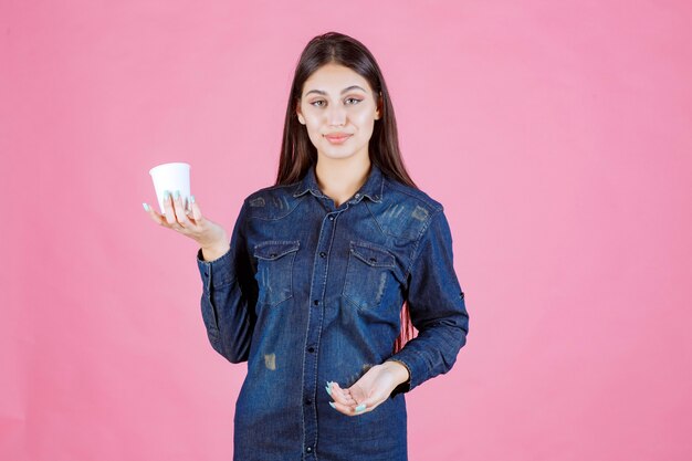 Chica en camisa de mezclilla sosteniendo una taza de café y se siente positiva