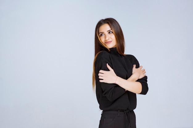 Chica en camisa negra dando poses atractivas y neutrales. Foto de alta calidad