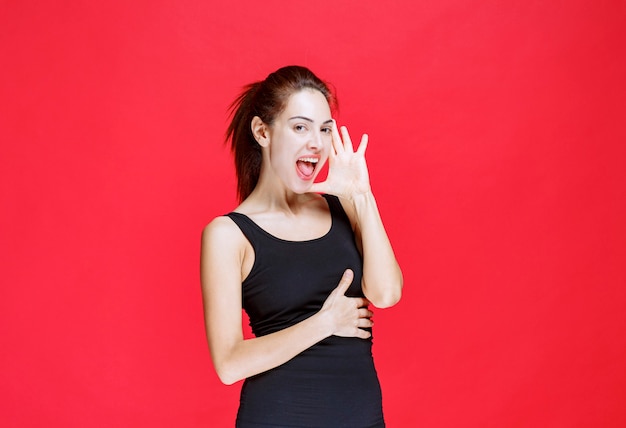 Chica en camisa negra riendo a carcajadas como una tonta. Foto de alta calidad